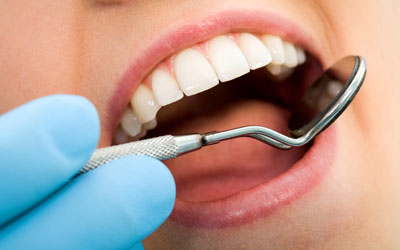 Dentist looking in woman's mouth with mirror