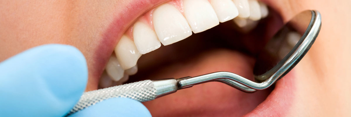 Dentist checking woman's teeth with hand mirror