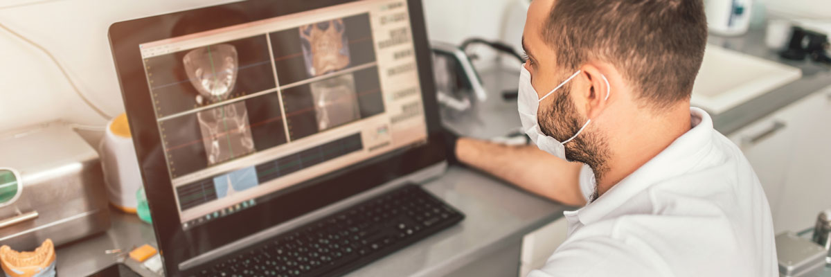 Dentist looking at digital x-rays on a screen