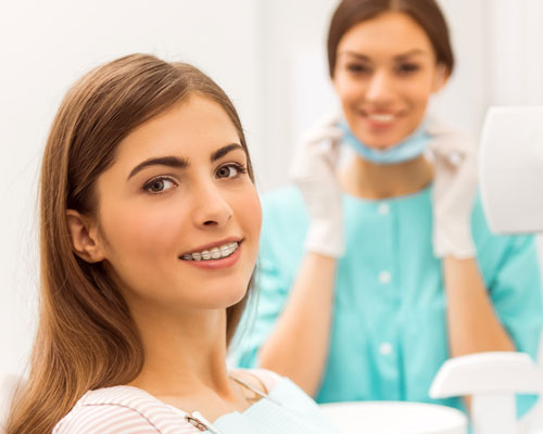 Adult woman with braces, female dentist in background out of focus