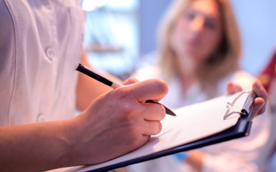 Dentist filling out medical forms, patient out of focus in background